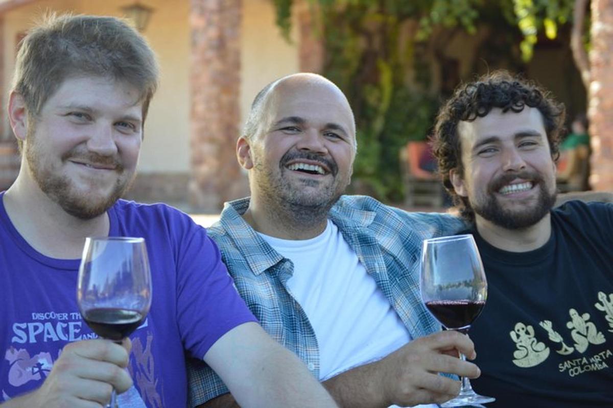tre uomini tengono in mano bicchieri di vino rosso