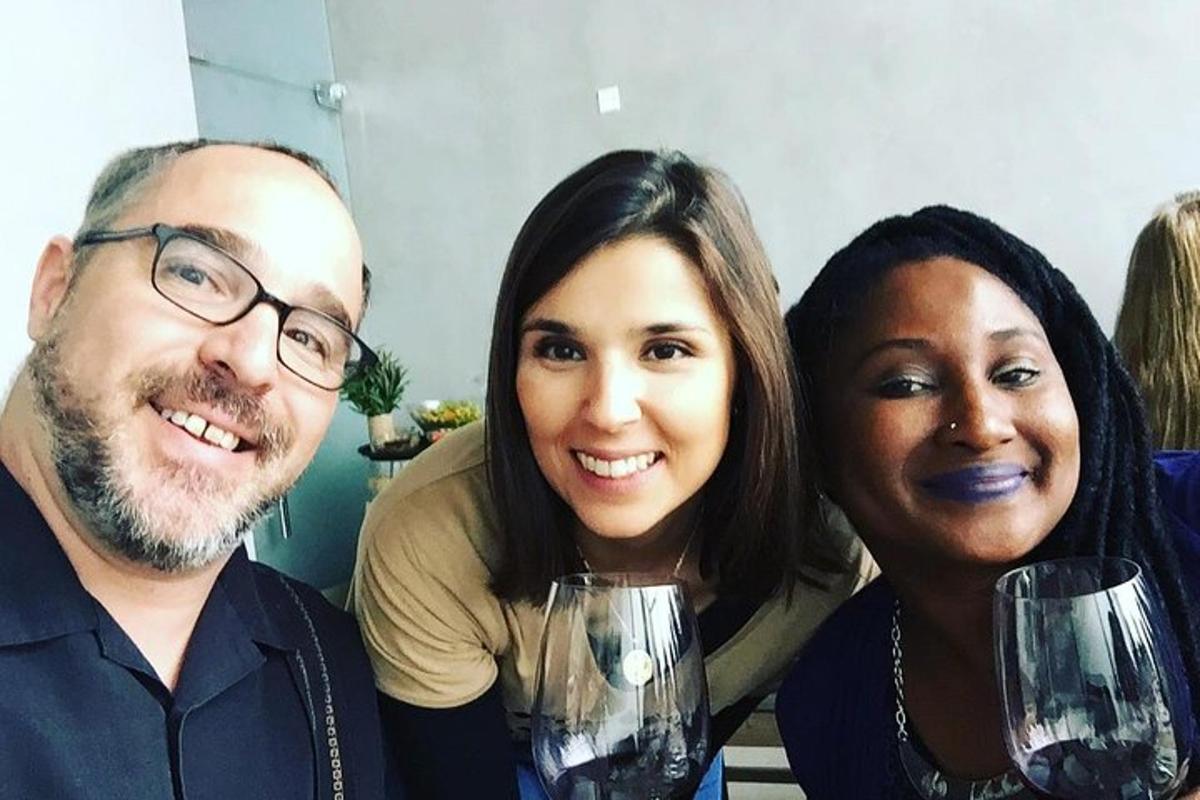 tre persone posano per una foto con bicchieri di vino