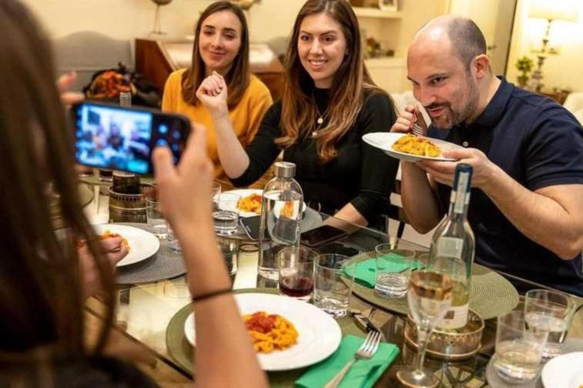 μια ομάδα ανθρώπων που κάθονται γύρω από ένα τραπέζι τρώγοντας φαγητό