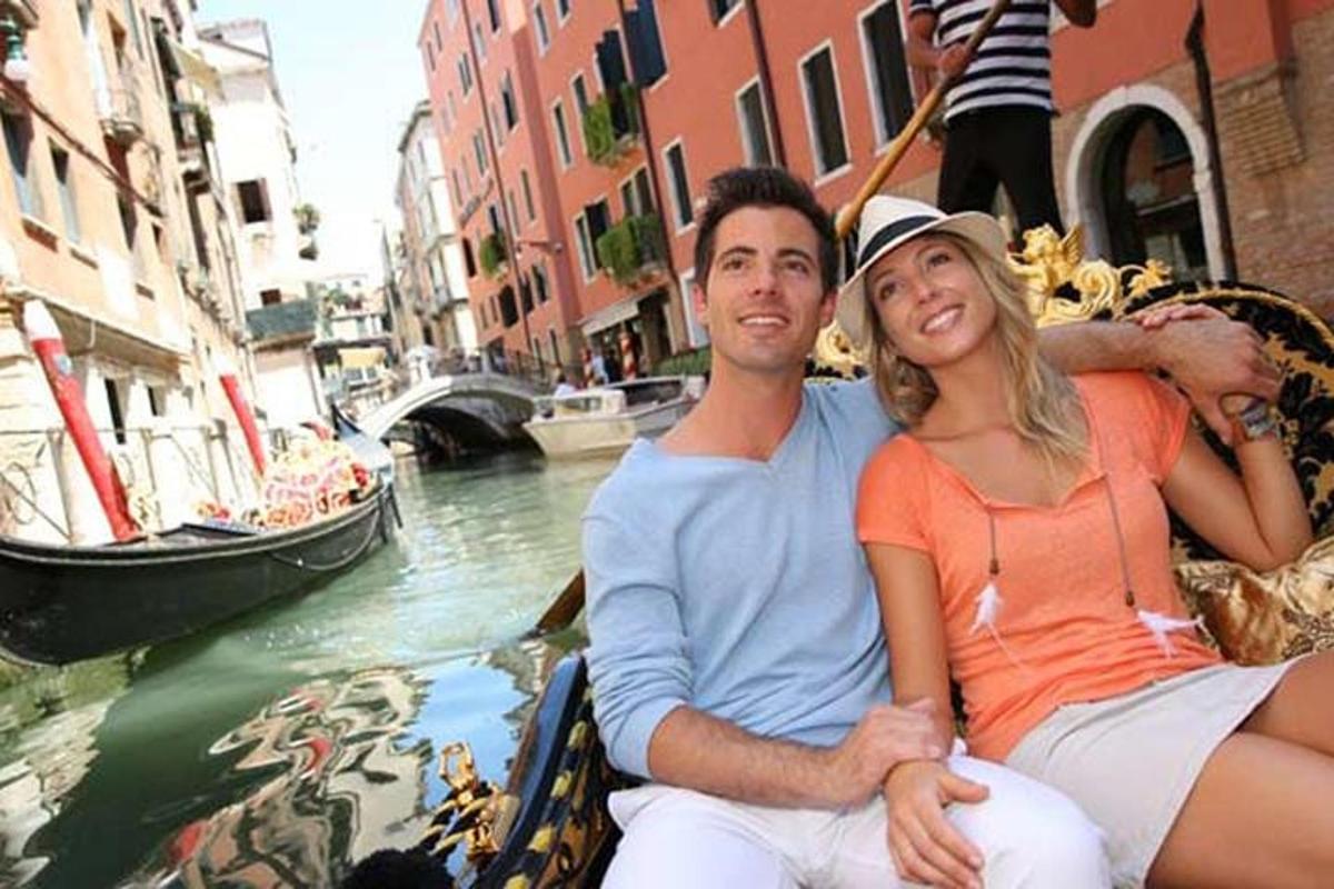 un home i una dona asseguts en una góndola en un canal