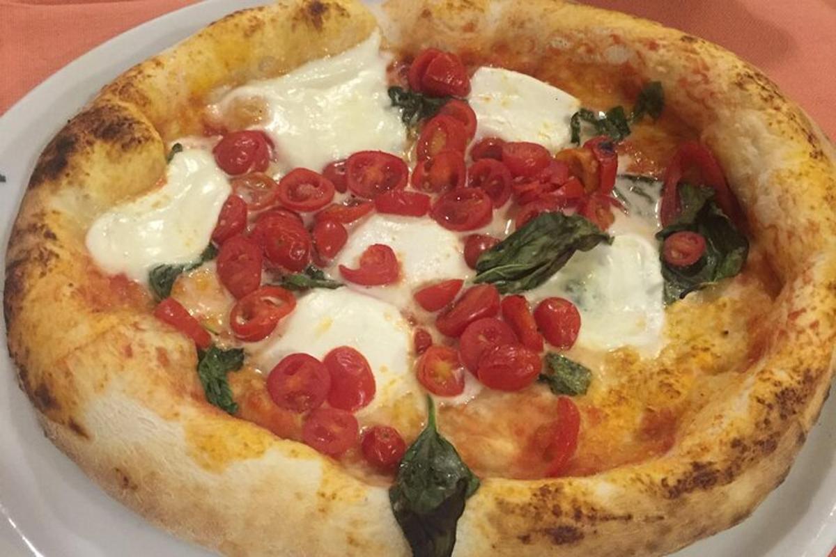 o pizza cu roșii și spanac pe o farfurie albă