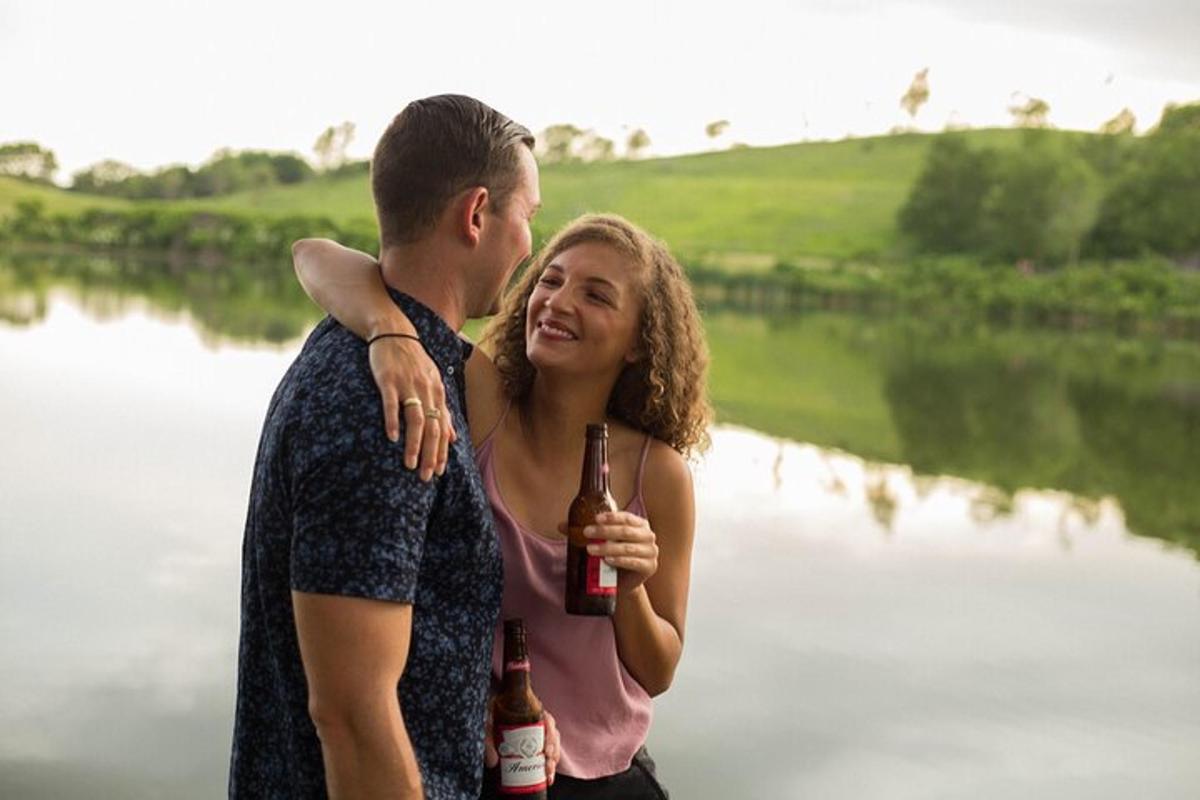 Ein Mann und eine Frau stehen neben einem Fluss und halten Bierflaschen