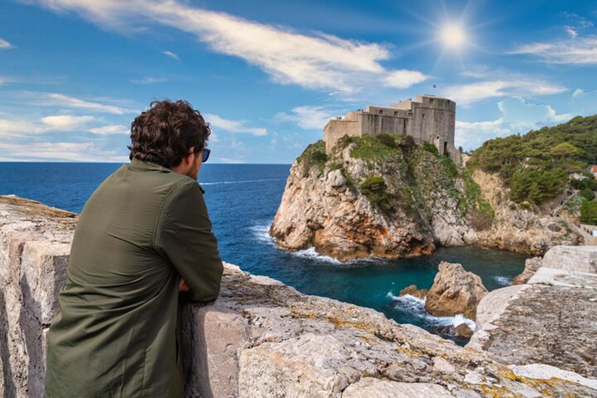 Un hombre sentado en un muro mirando un castillo.