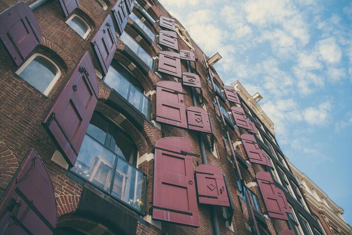 Un edificio alto de ladrillo con persianas rosas.