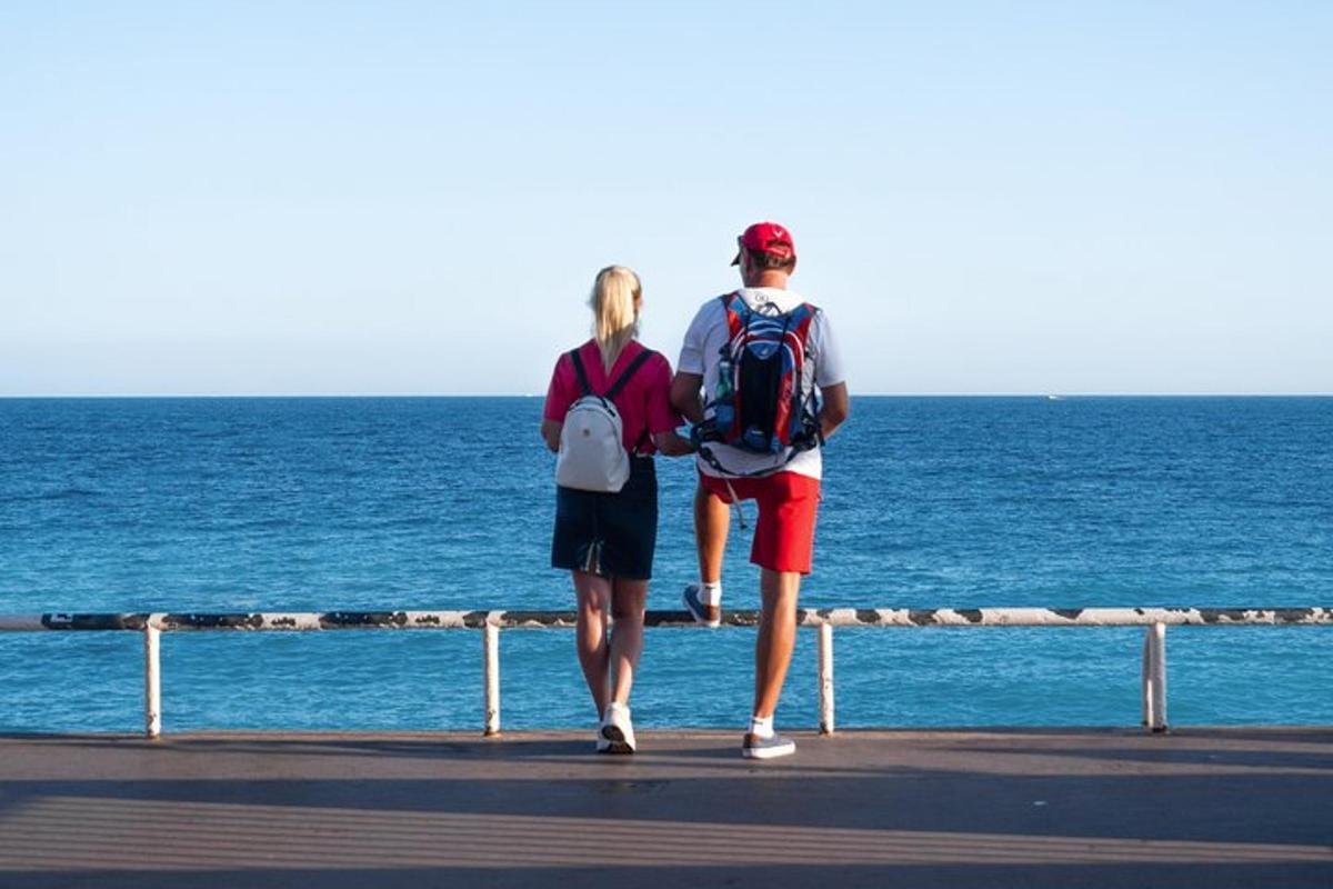 un uomo e una donna che camminano su un molo guardando l'oceano