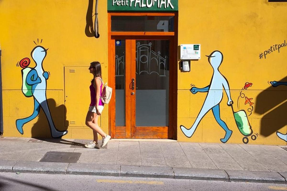 žena kráčející po chodníku před budovou s graffiti