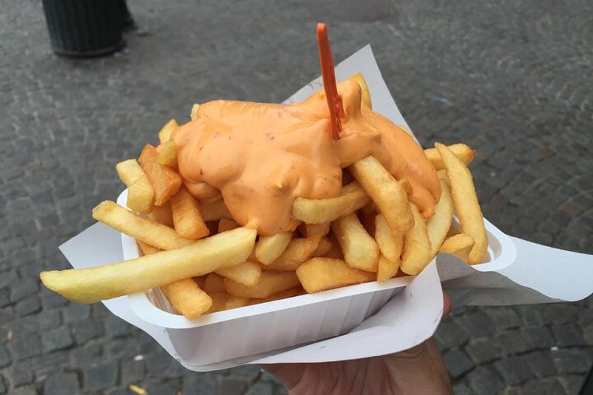 maður heldur á bakka af frönskum kartöflum og samloku