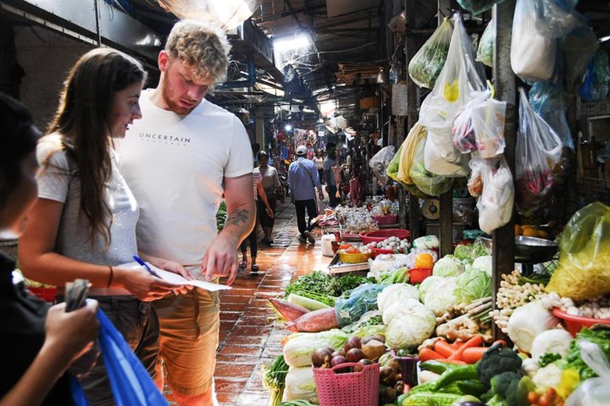 Un hombre y una mujer de pie en un mercado con verduras.