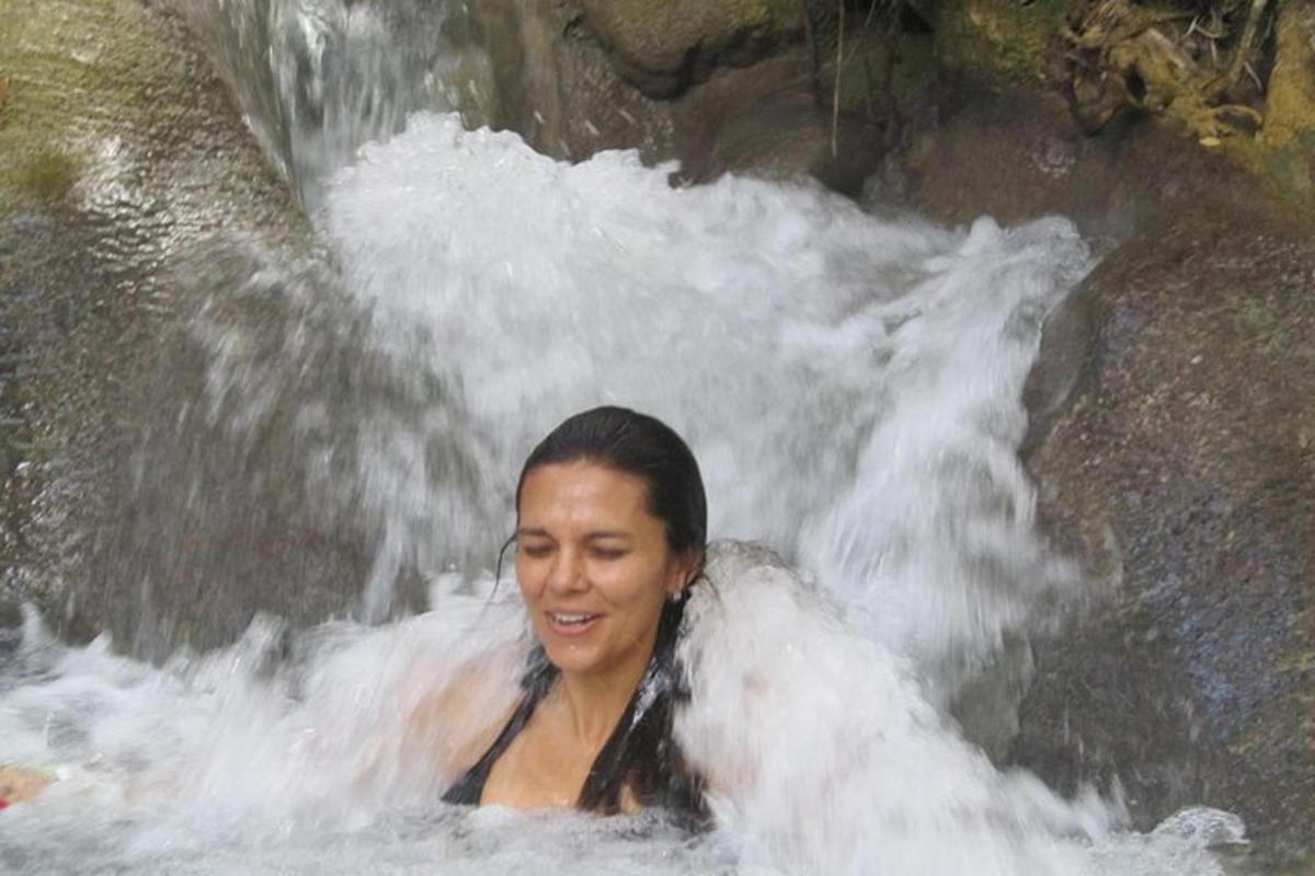 Una mujer está en una cascada en el agua.
