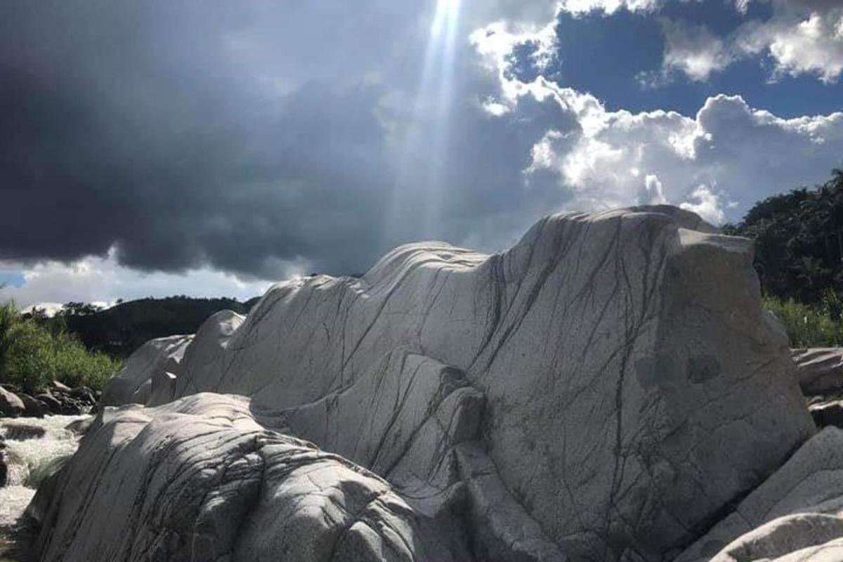 a large rock formation on a beach with the sun