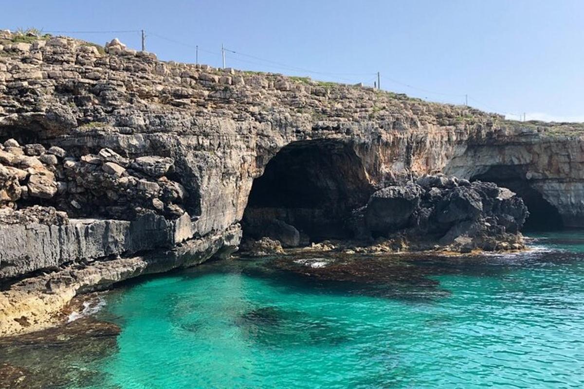 Una cueva en la ladera de un acantilado con agua azul.