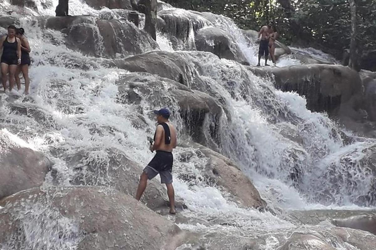 a man standing on rocks in front of a waterfall