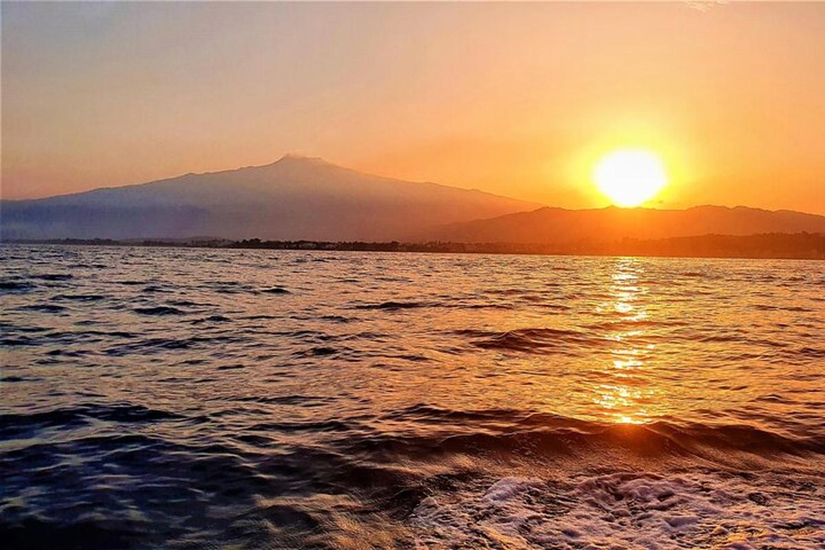 um pôr do sol sobre um corpo d'água com uma montanha