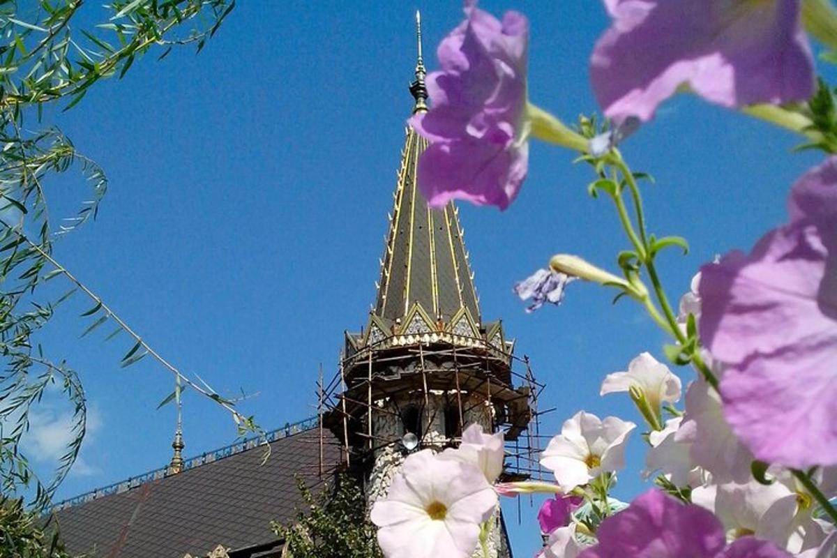 a tower with a spire in the background with purple flowers