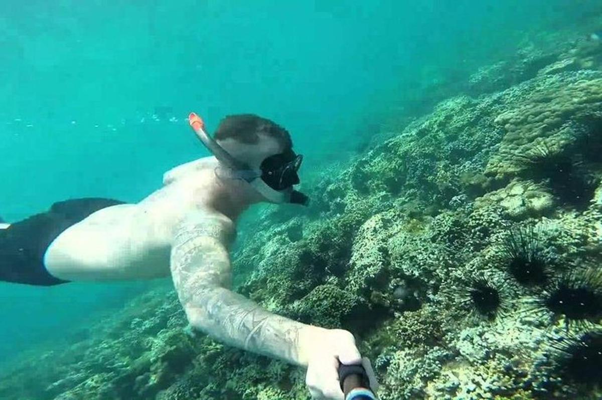 muž s tetováním na paži plave v oceánu