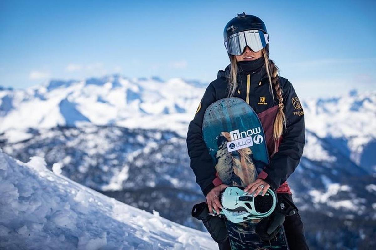 a woman holding a snowboard on top of a mountain