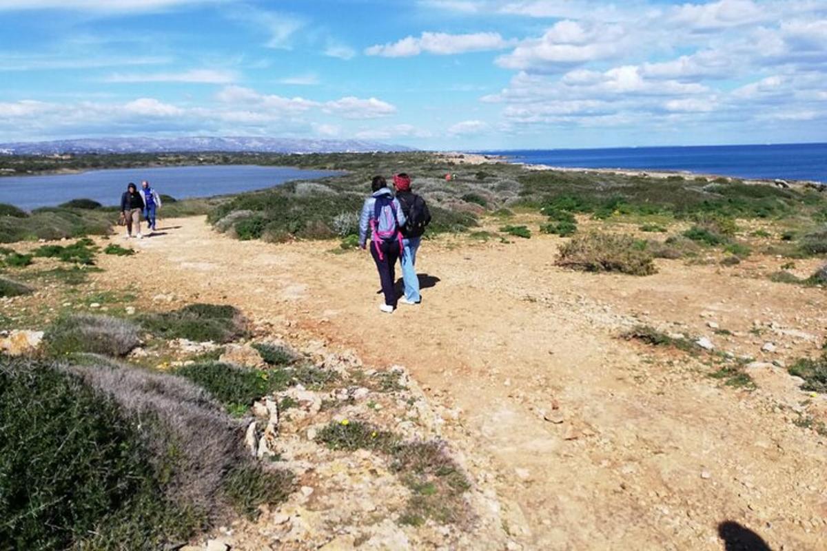 un gruppo di persone che cammina su una strada sterrata vicino all'acqua