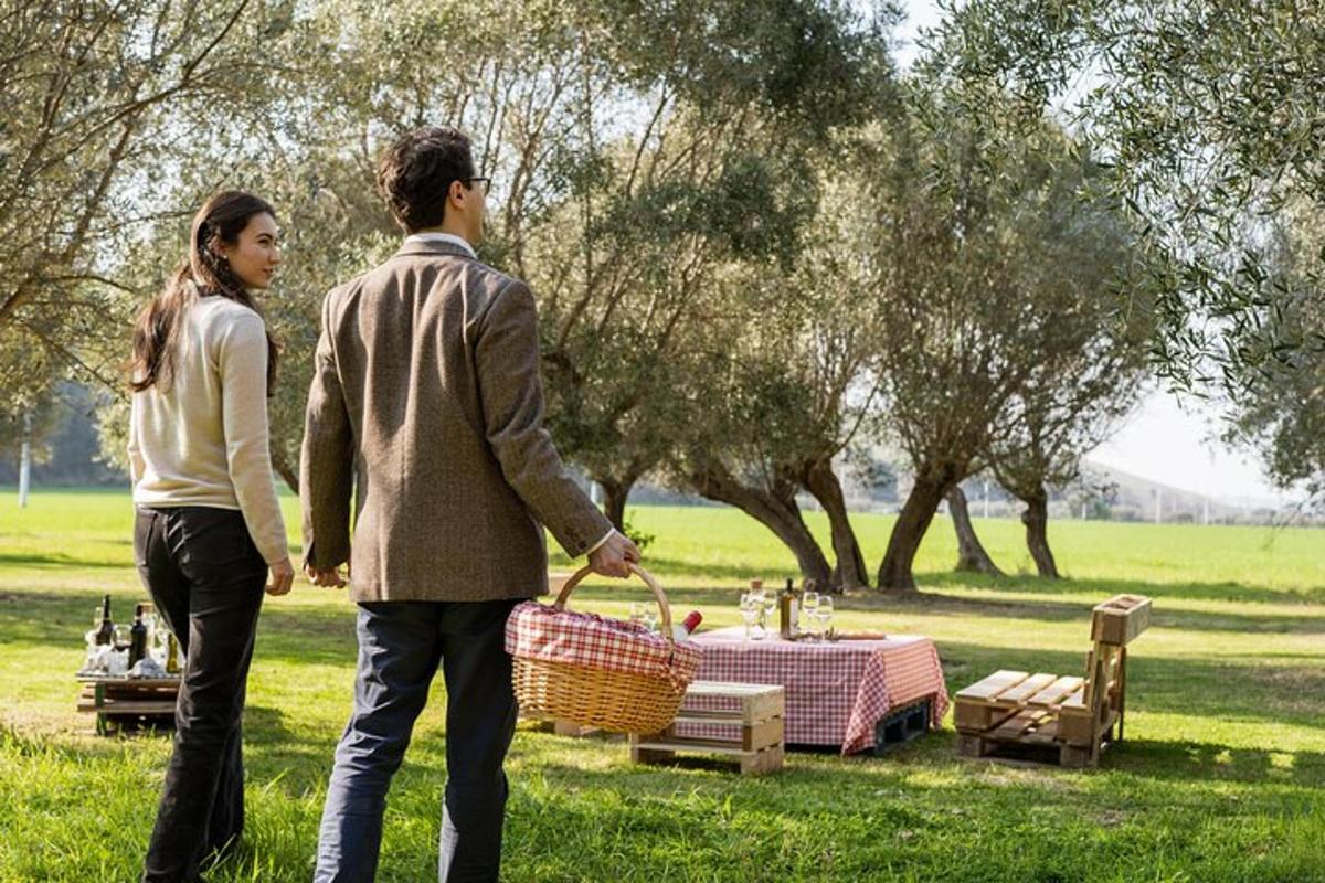 a man and woman walking in a park with a picnic basket