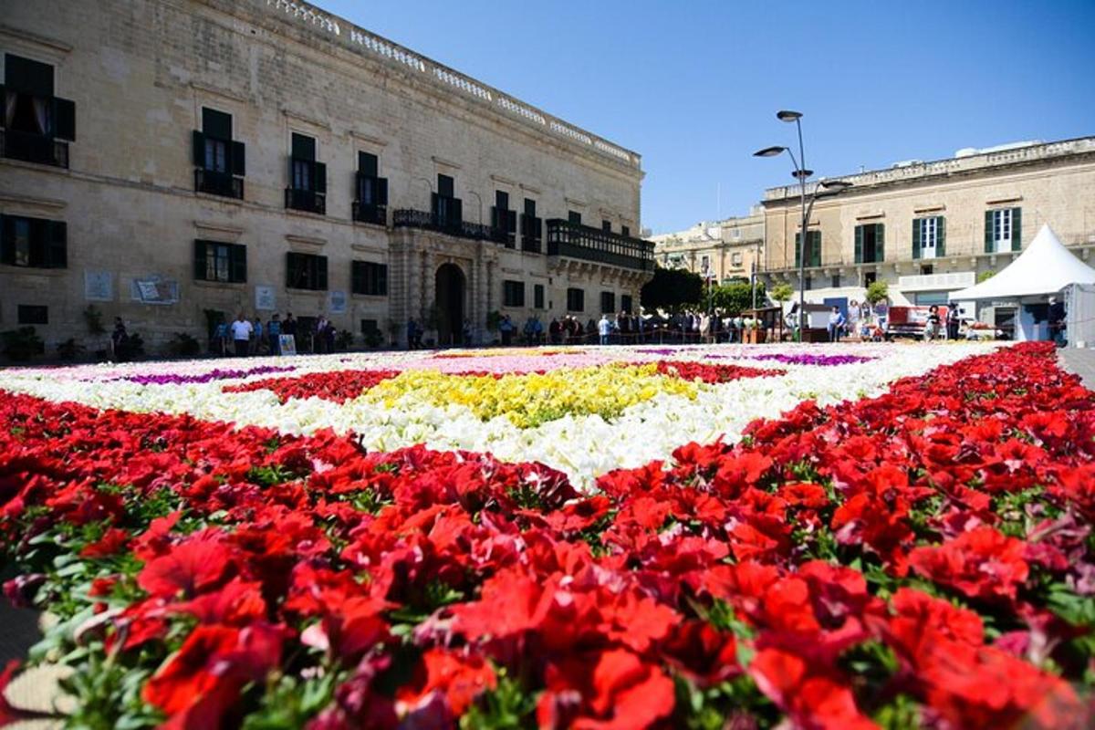 a field of red and white flowers in front of a building