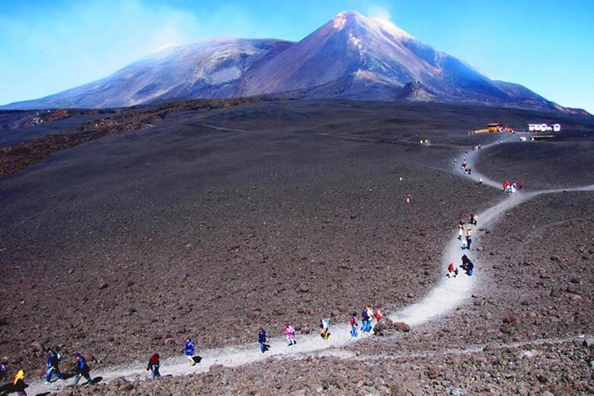 a group of people walking on a path in front of a mountain