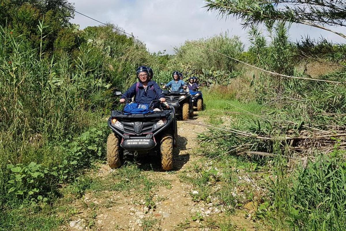 Tre personer som kjører ATV på en grusvei