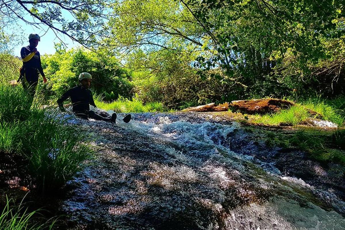 two people are sitting on the side of a river