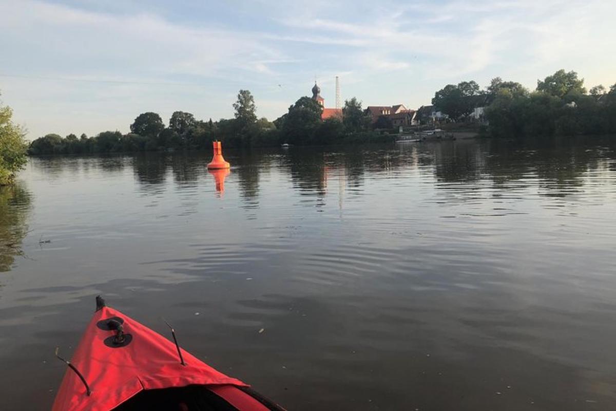 a red kayak on a lake with a orange buoy