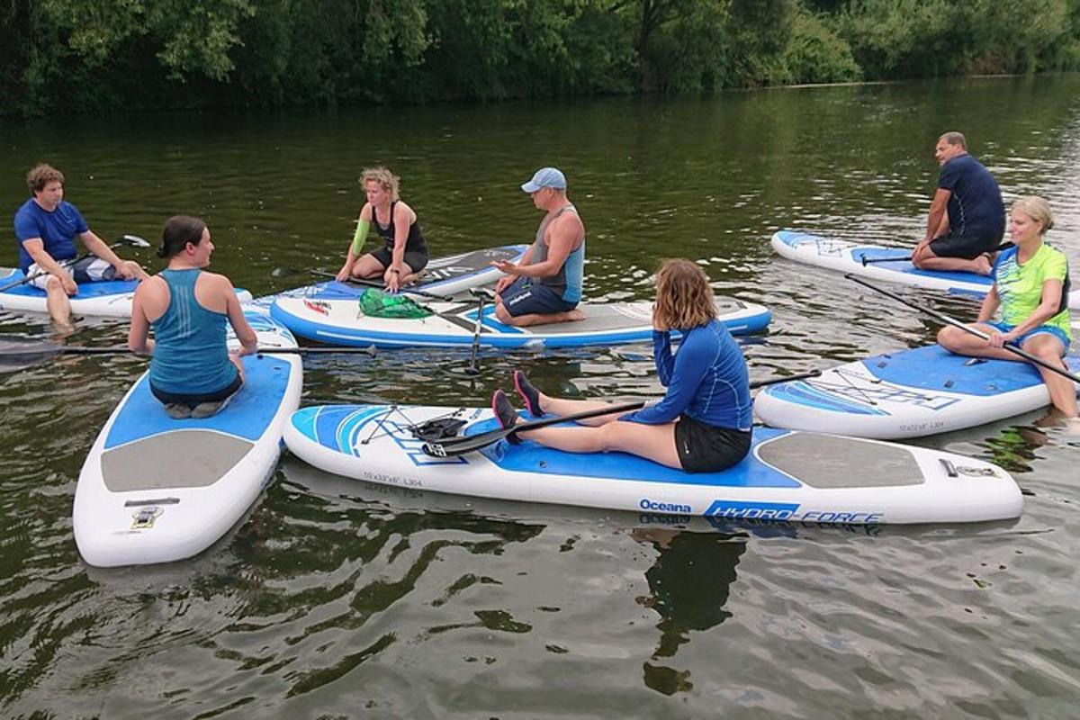 skupina lidí sedících na paddleboardech ve vodě
