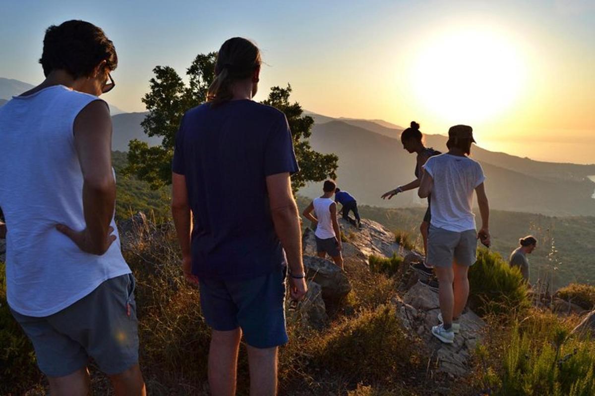 a group of people standing on a mountain watching the sunset