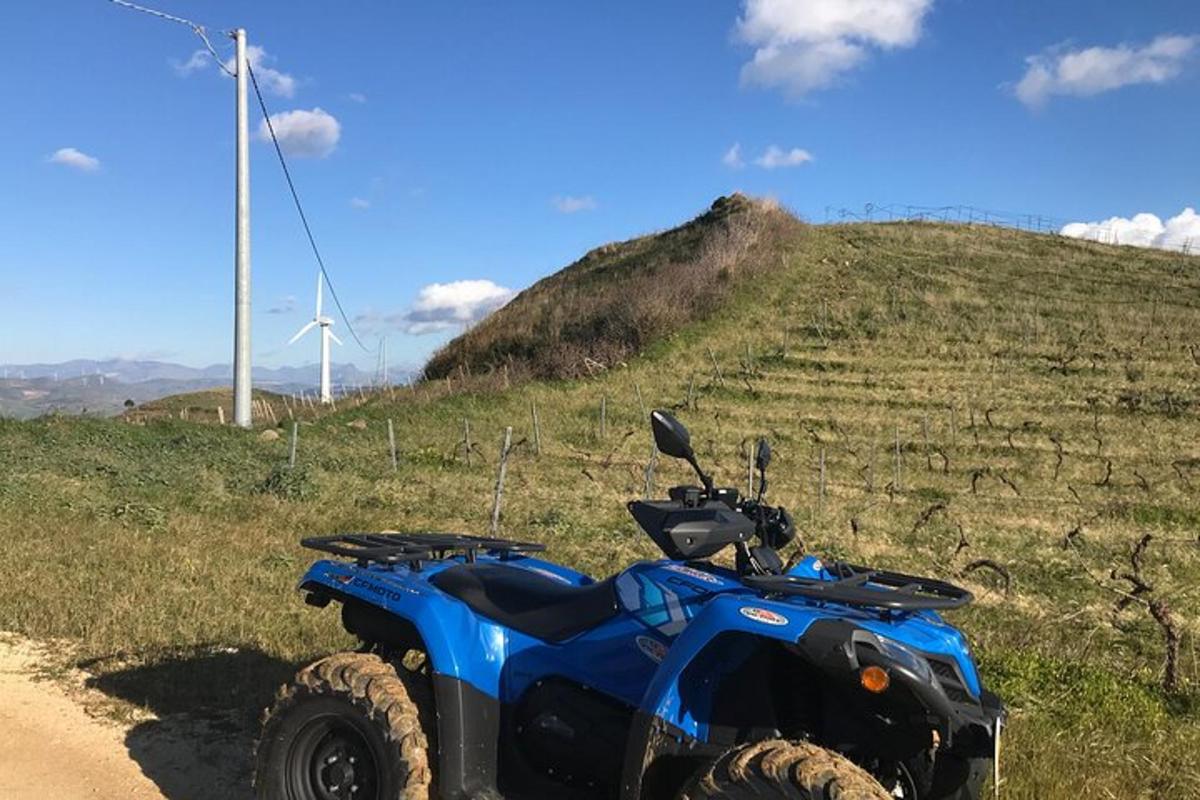 moder štirikolesnik parkiran na makadamski cesti na polju