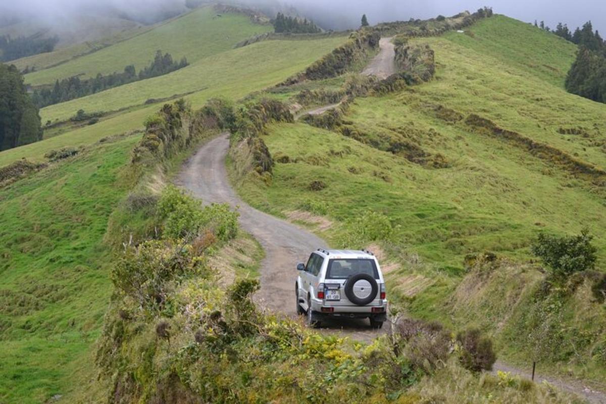 un'auto che percorre una strada sterrata su una collina