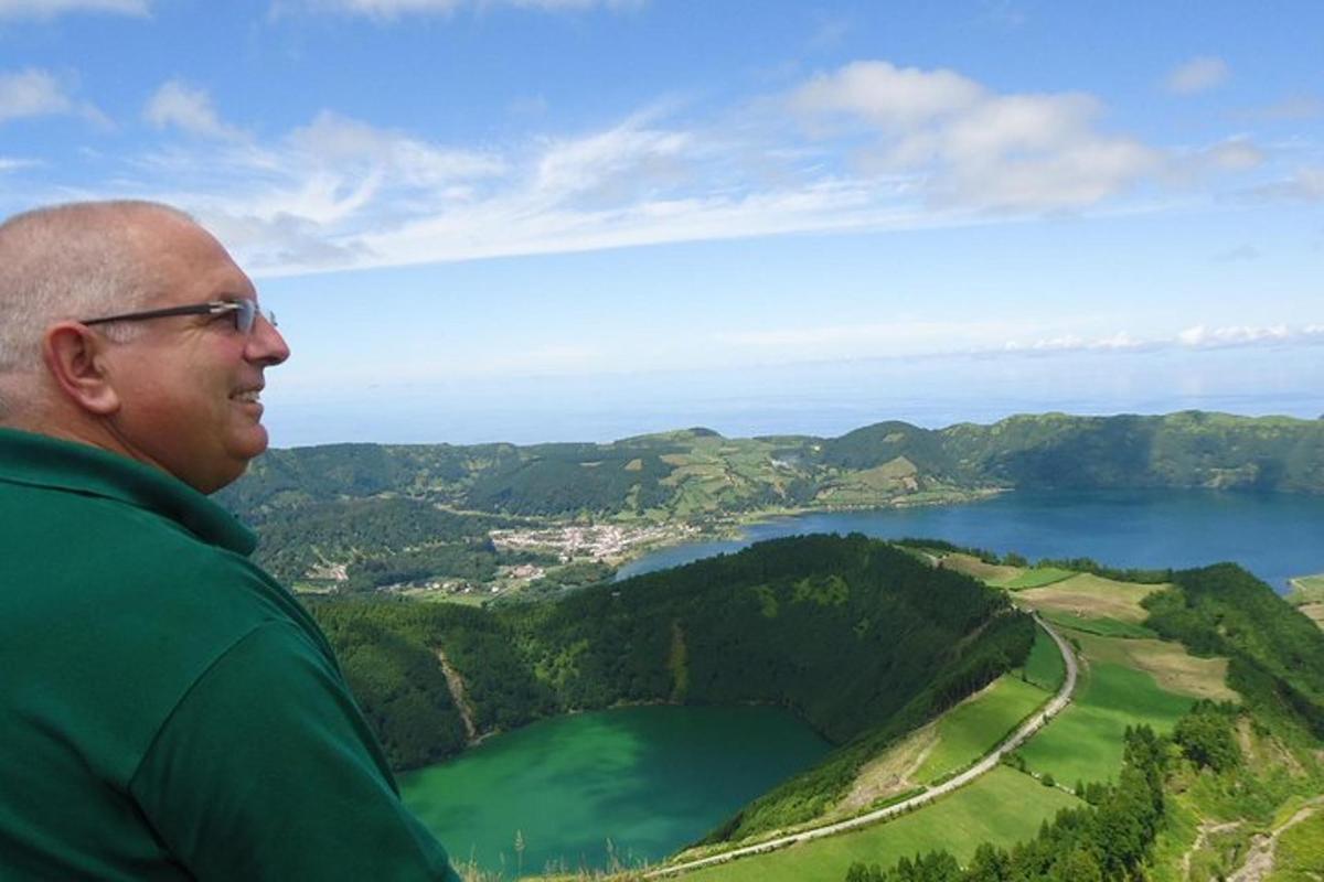 muž stojící na vrcholu kopce s výhledem na jezero