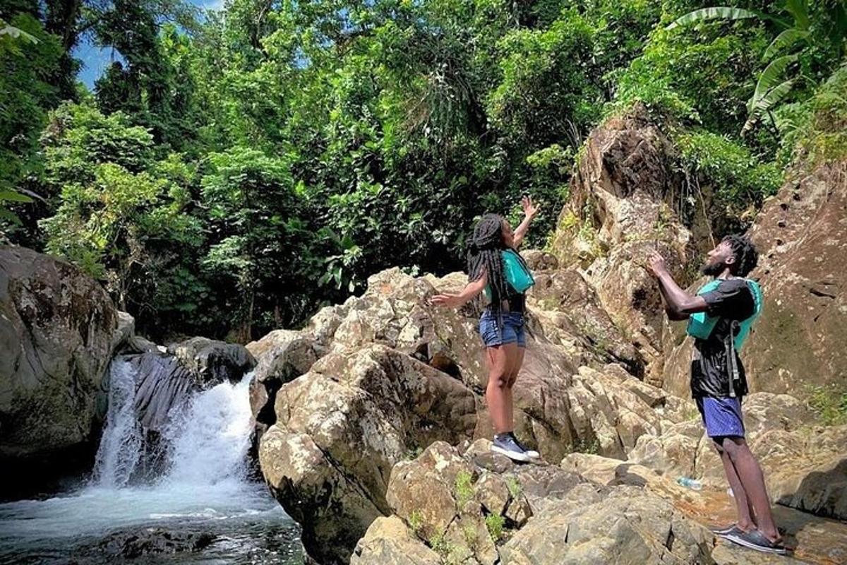 two people standing on rocks near a waterfall