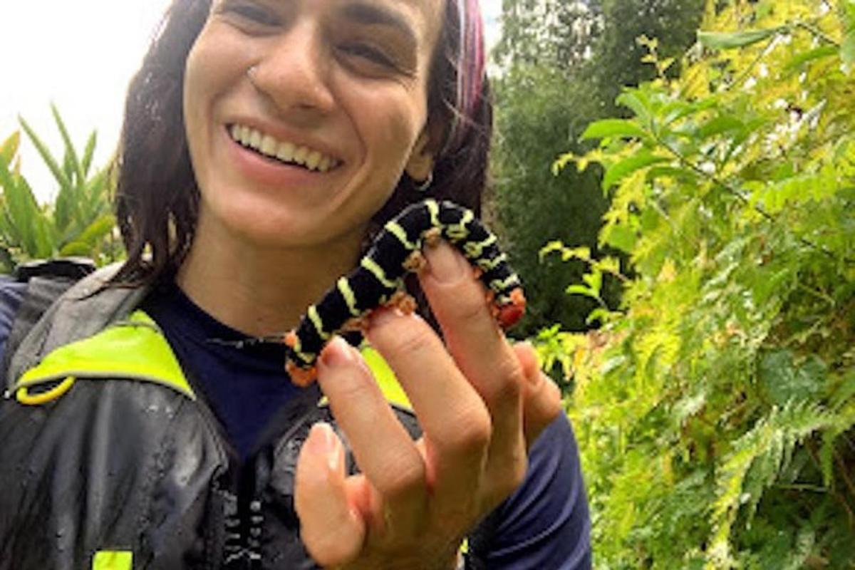 a woman is smiling while holding a caterpillar