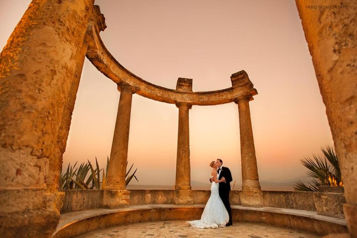 pasangan pengantin bercium di hadapan gerbang batu