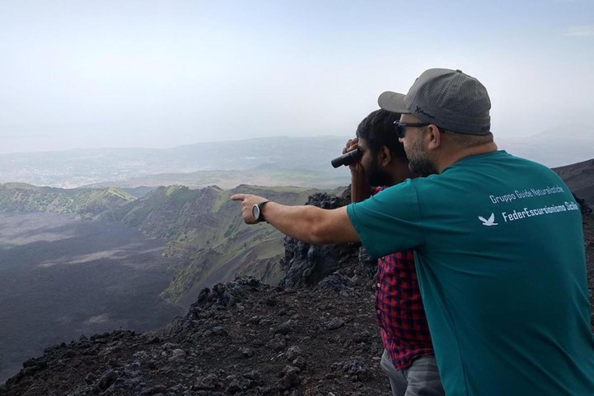 um homem apontando para a vista do topo de uma montanha
