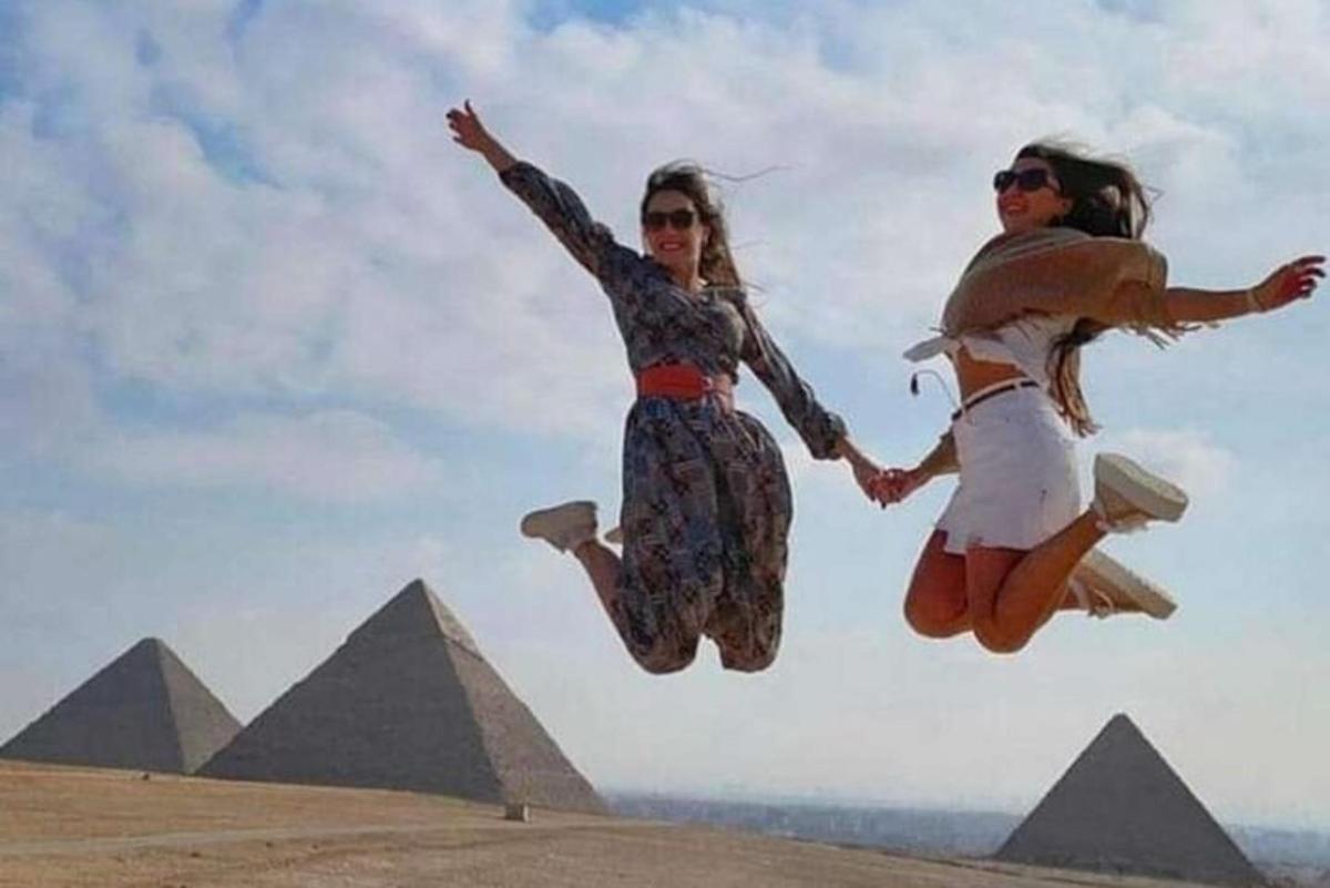 Dvě dívky skákající do vzduchu před pyramidami