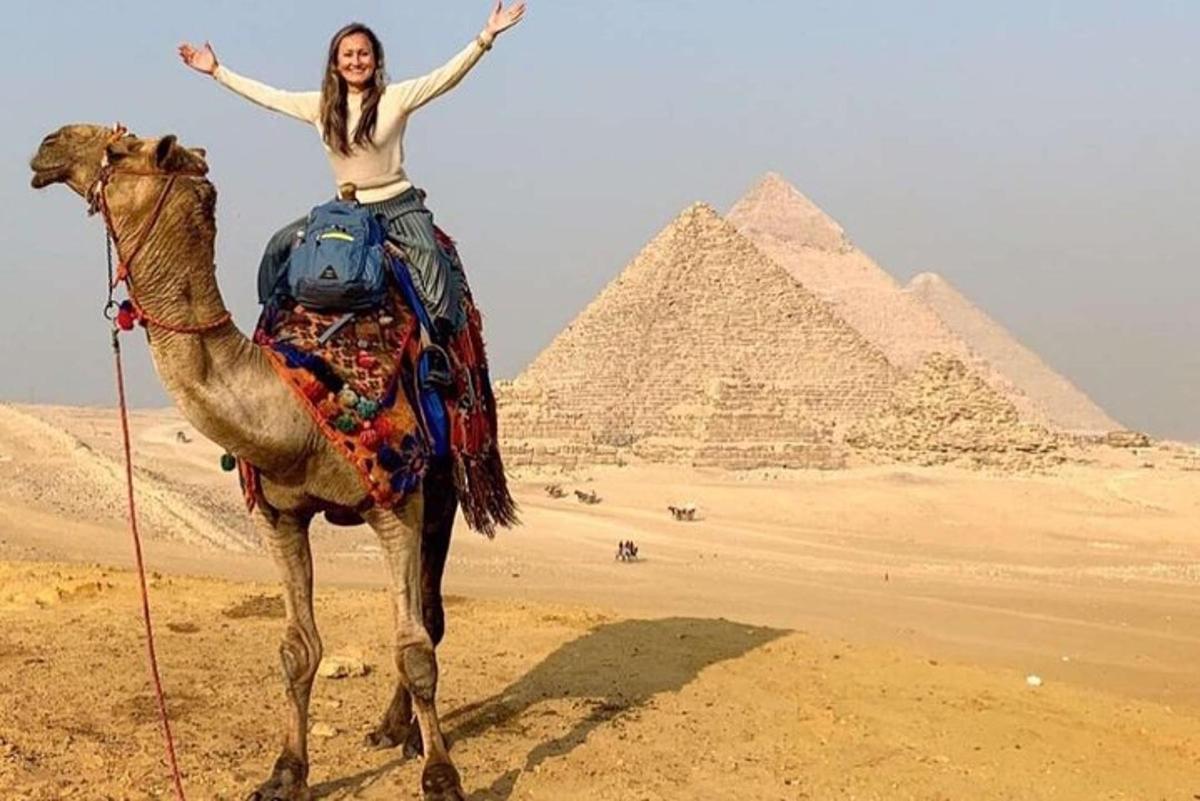 žena jedoucí na velbloudovi před pyramidami