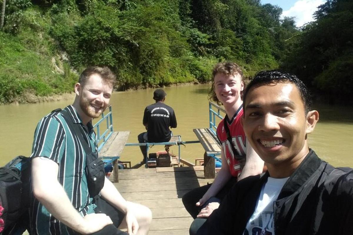 tiga lelaki duduk di atas dok di sungai