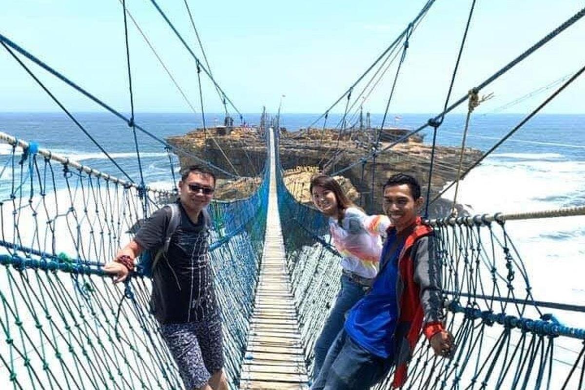 tre persone su un ponte sospeso sopra l'oceano