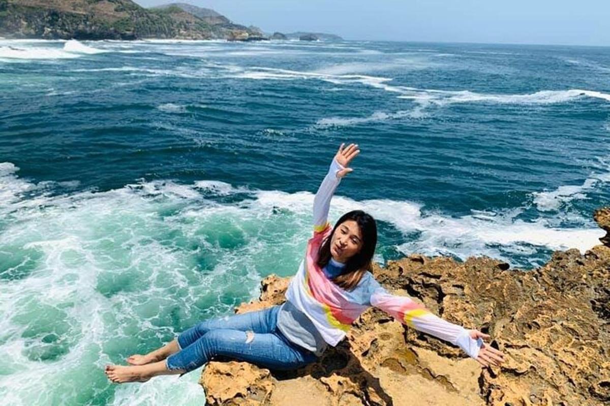 una donna sdraiata su una roccia in riva all'oceano