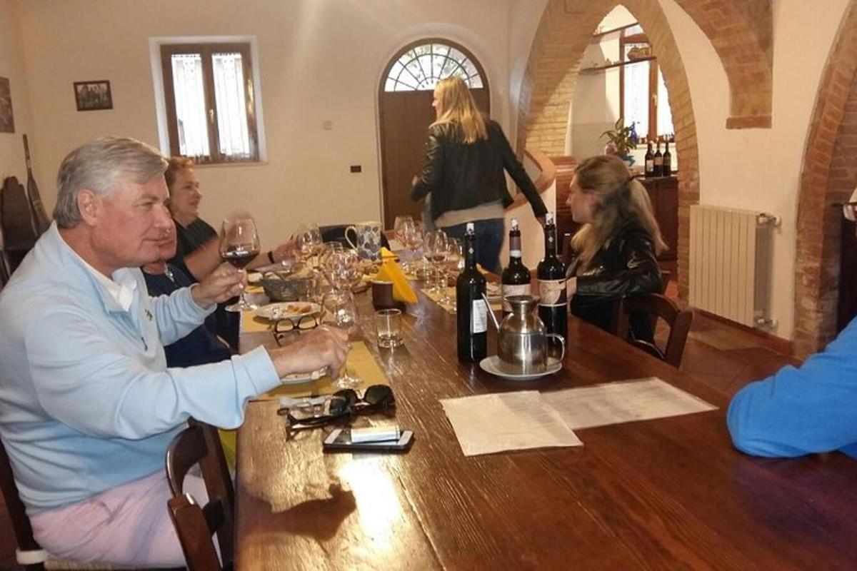 un grup de oameni așezați în jurul unei mese cu pahare de vin