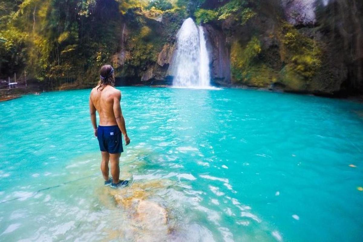 un uomo in piedi nell'acqua di fronte a una cascata