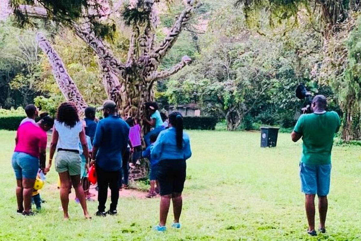 un grup de persones dretes en un camp mirant una girafa