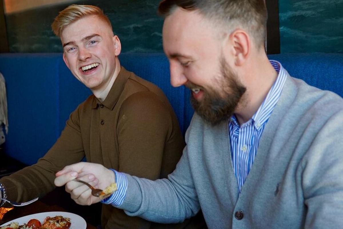 Dos hombres sentados en una mesa con un plato de comida.