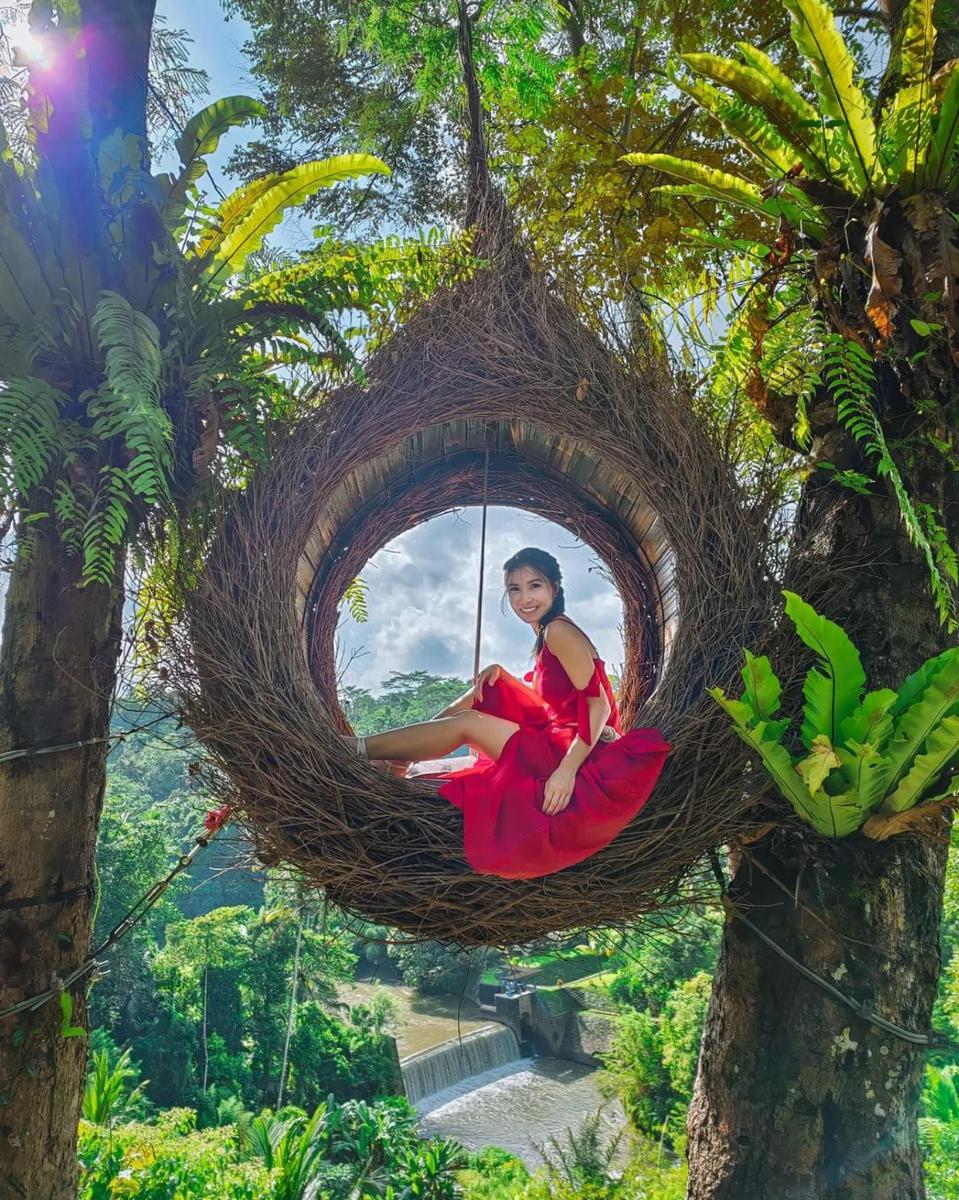 una mujer sentada en un nido colgado de un árbol