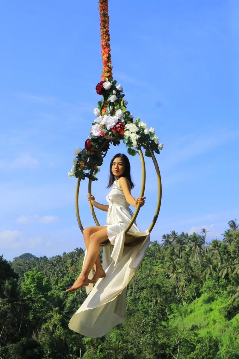 a girl is sitting on a swing with flowers