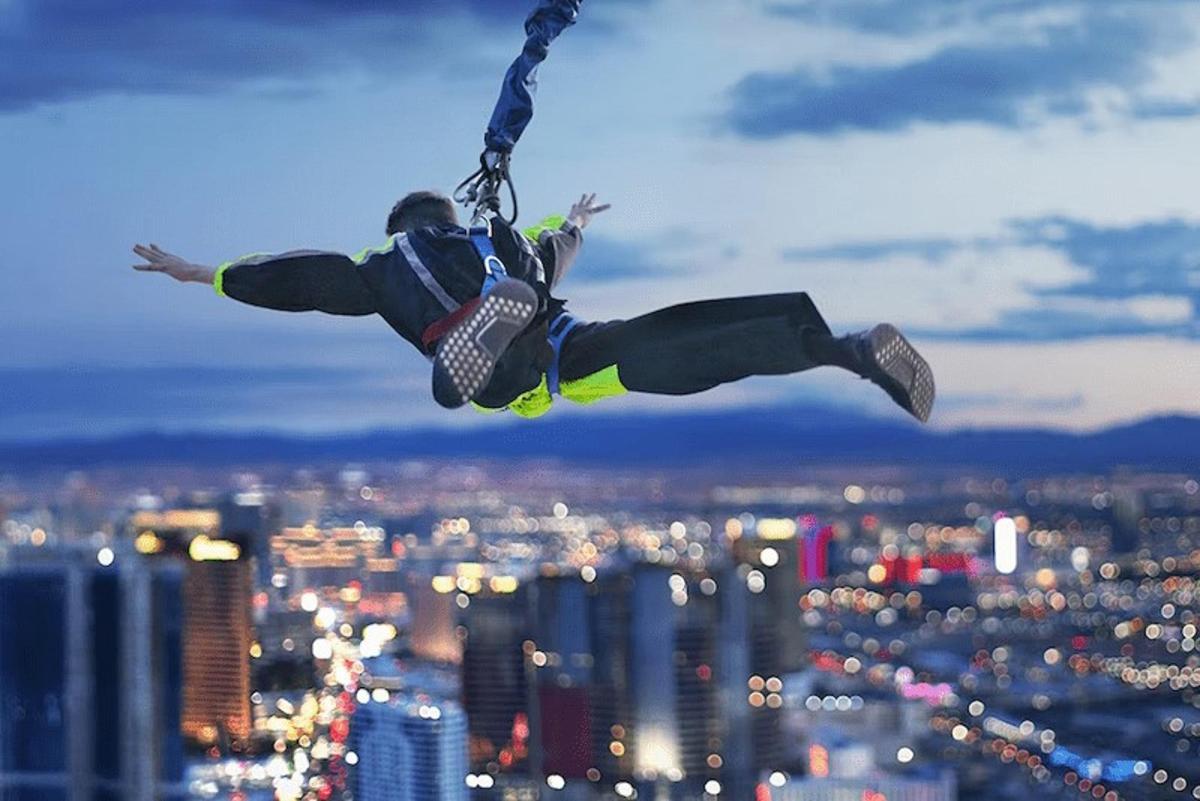 a man is hanging from a chain on top of a city