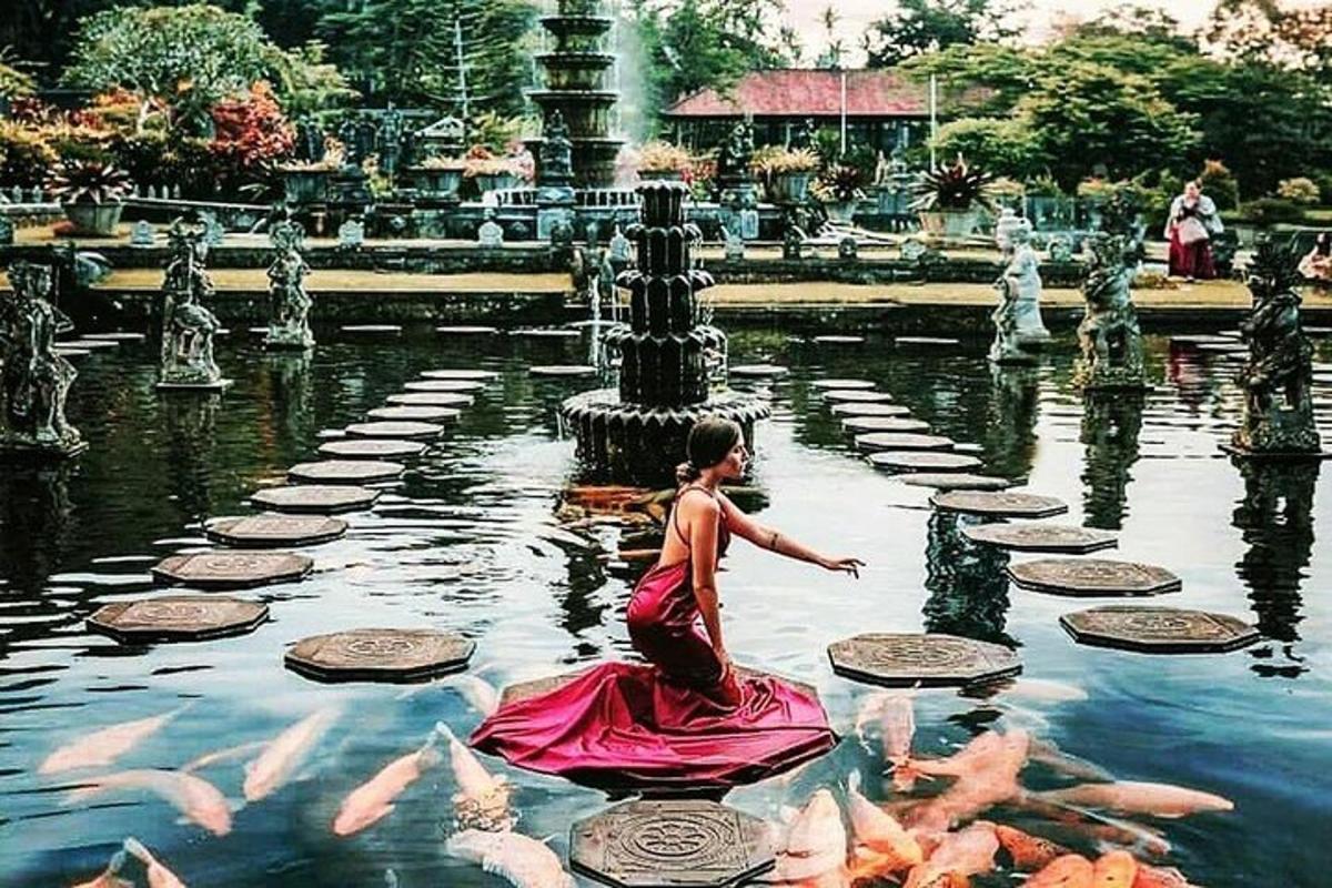 Una niña con un vestido rosa en un estanque con peces.