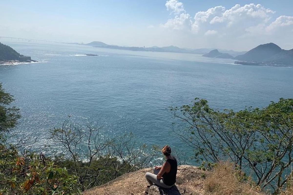 žena sedící na útesu a dívající se na oceán